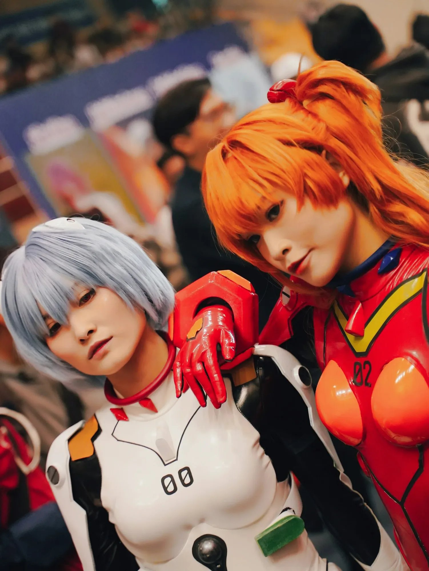 Two cosplayers in white and orange costumes posing together.
